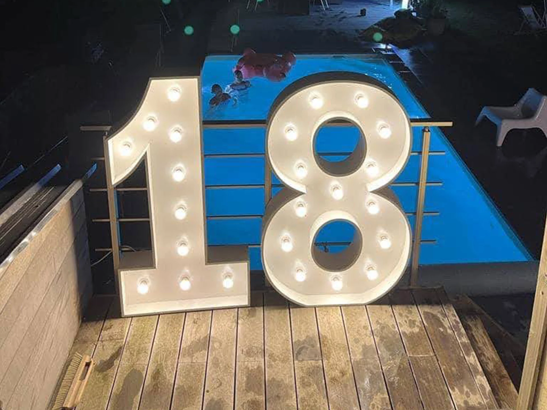 Chiffre 18 lumineux au bord d’une piscine