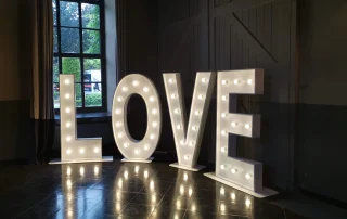 Lettres LOVE lumineuses dans une salle sombre avec reflets au sol Lettres LOVE lumineuses dans une salle sombre avec reflets au sol