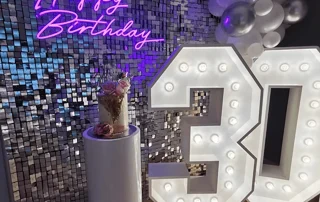Chiffre 30 lumineux devant un mur à paillettes