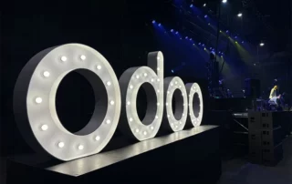 Odoo logo in light-up letters on a stage
